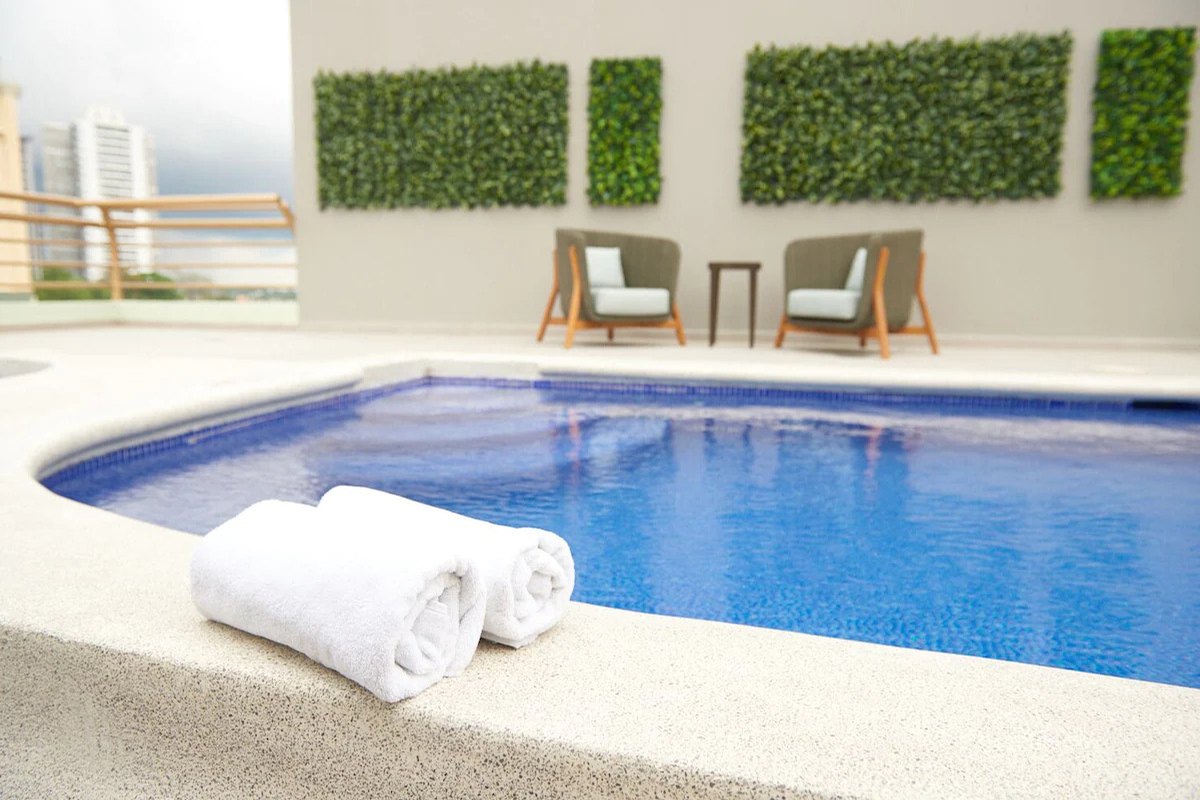 Piscina de Suites Las Palmas con toallas al borde y jardín vertical
